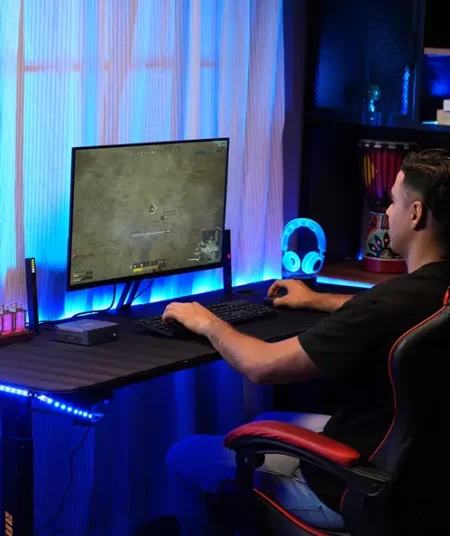 A man is playing games with GEEKOM mini PC.